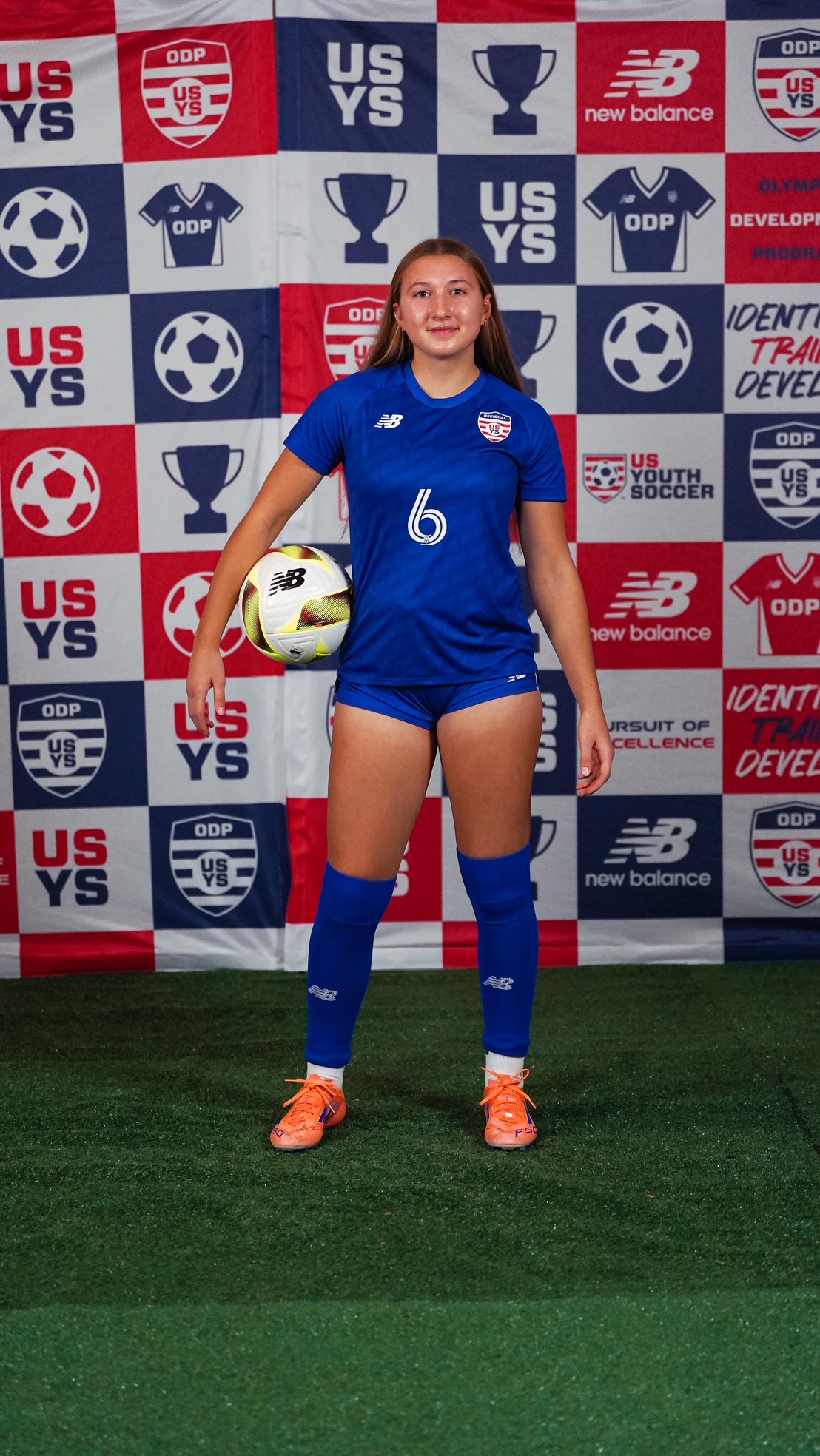 Ella Rust in a blue number 6 kit holding a soccer ball at an Olympic Development Program photo session.