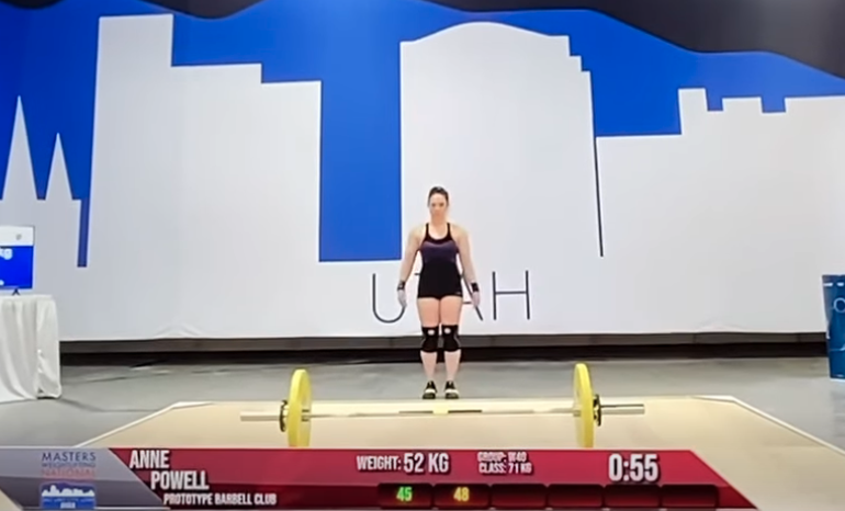 Annie Powell competing on the platform for Prototype Barbell Club