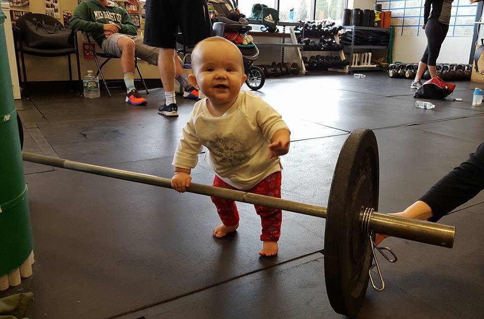 Baby Brianna walking at Prototype next to a barbell