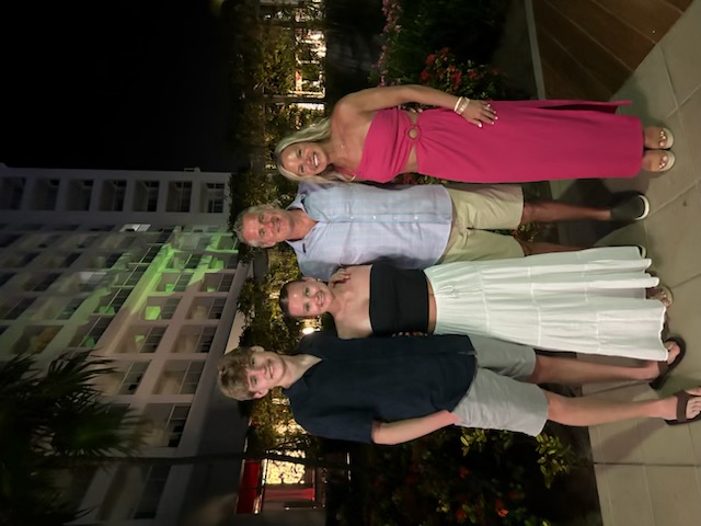 Tim Furbush smiling with his wife and two kids on a beach vacation