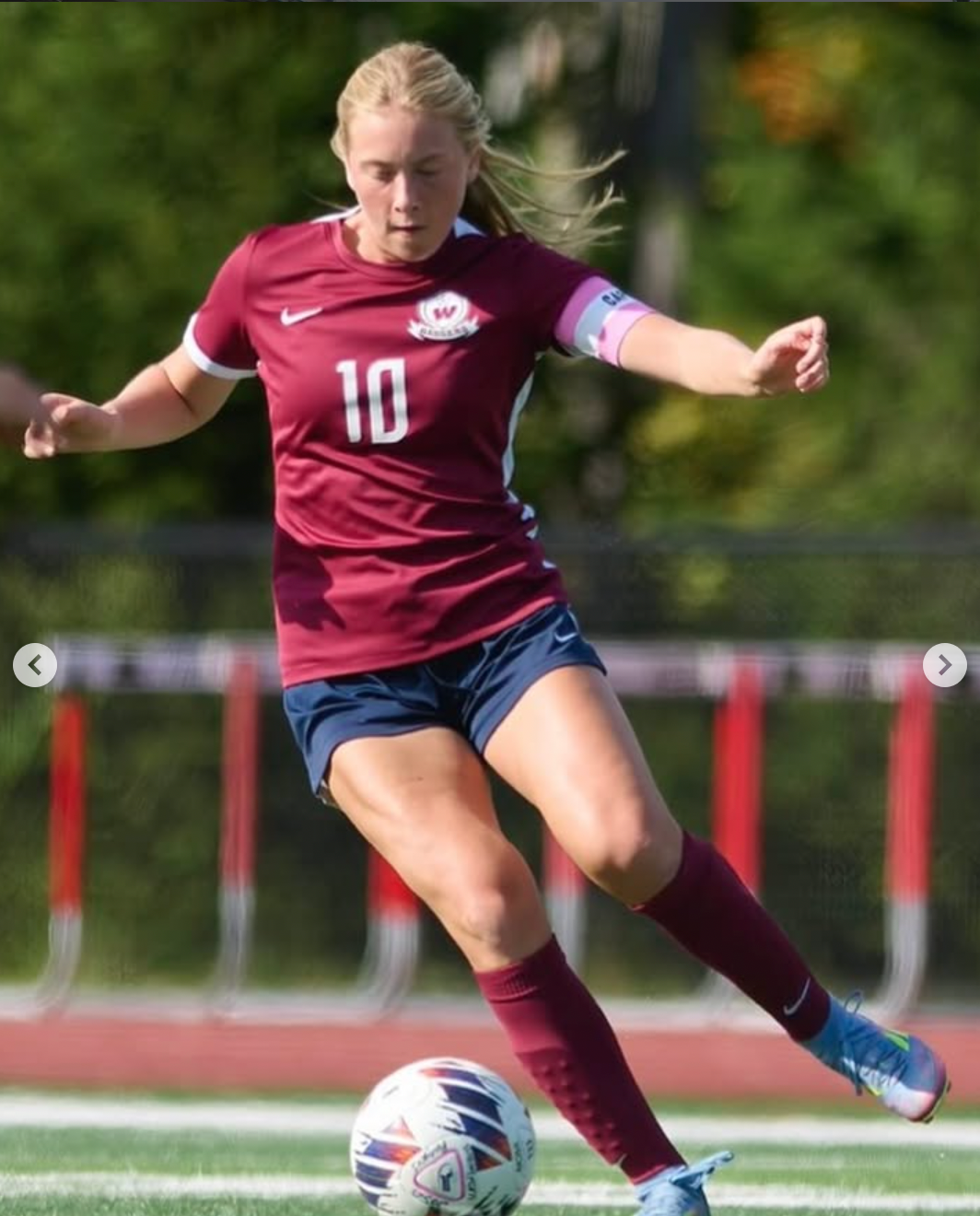 Caroline Queenan, wearing the number 10 captain's kit for Westborough varsity soccer, striking a soccer ball in a game.