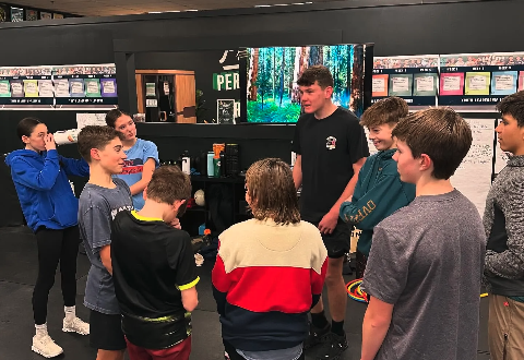 Junior Coach Owen leading a huddle of LTAD athletes on the training floor at Prototype.